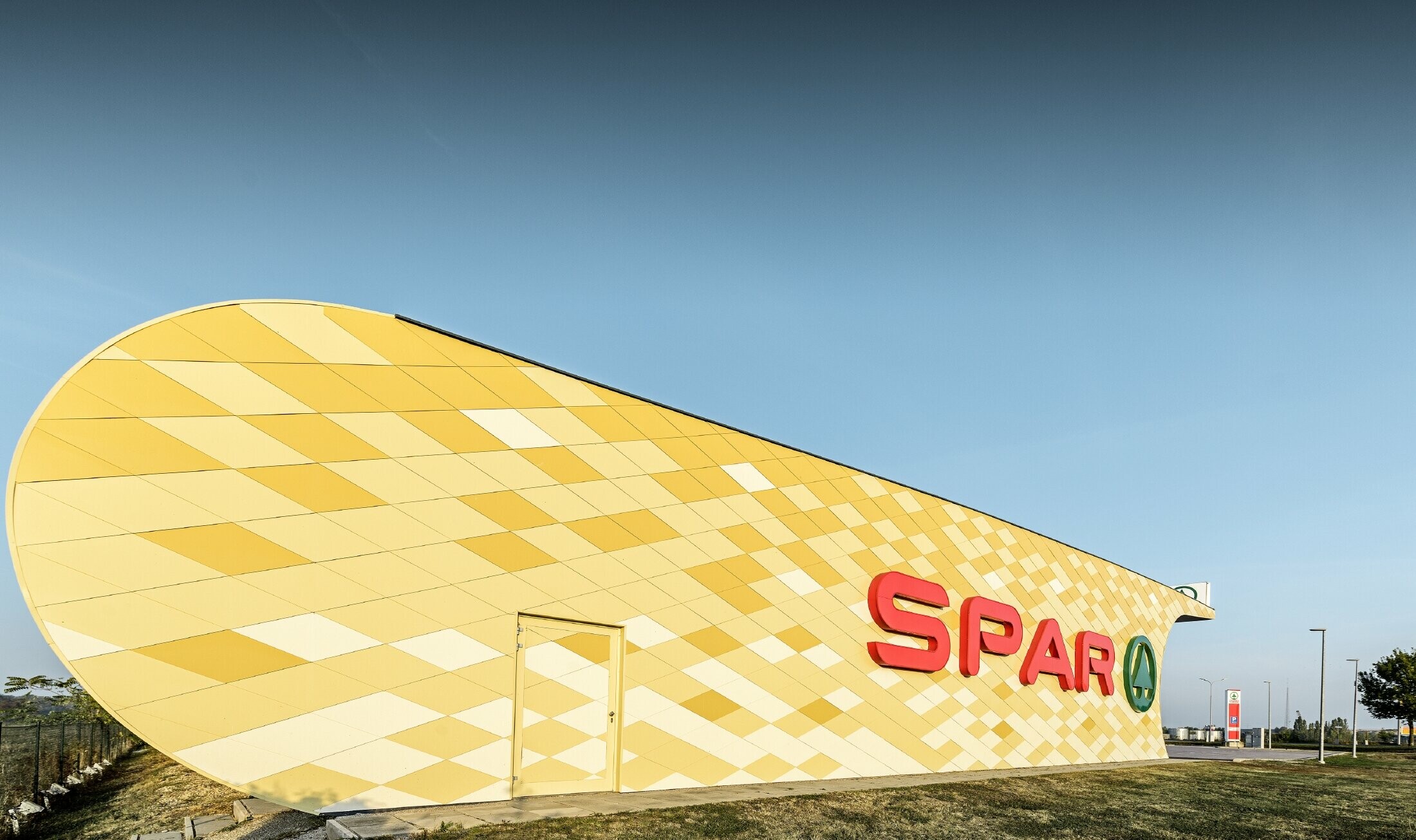 Spar áruház narancssárga alumínium homlokzattal és Spar-logóval