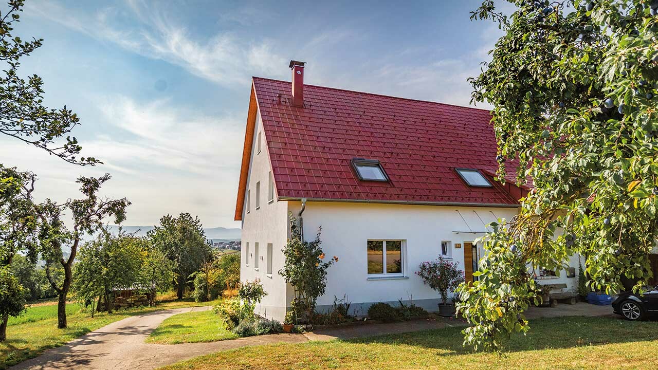 Romantisches Häuschen am land mit viel Bäumen und Sträuchern. Eingedeckt mit einem PREFA Dach in Oxydrot.