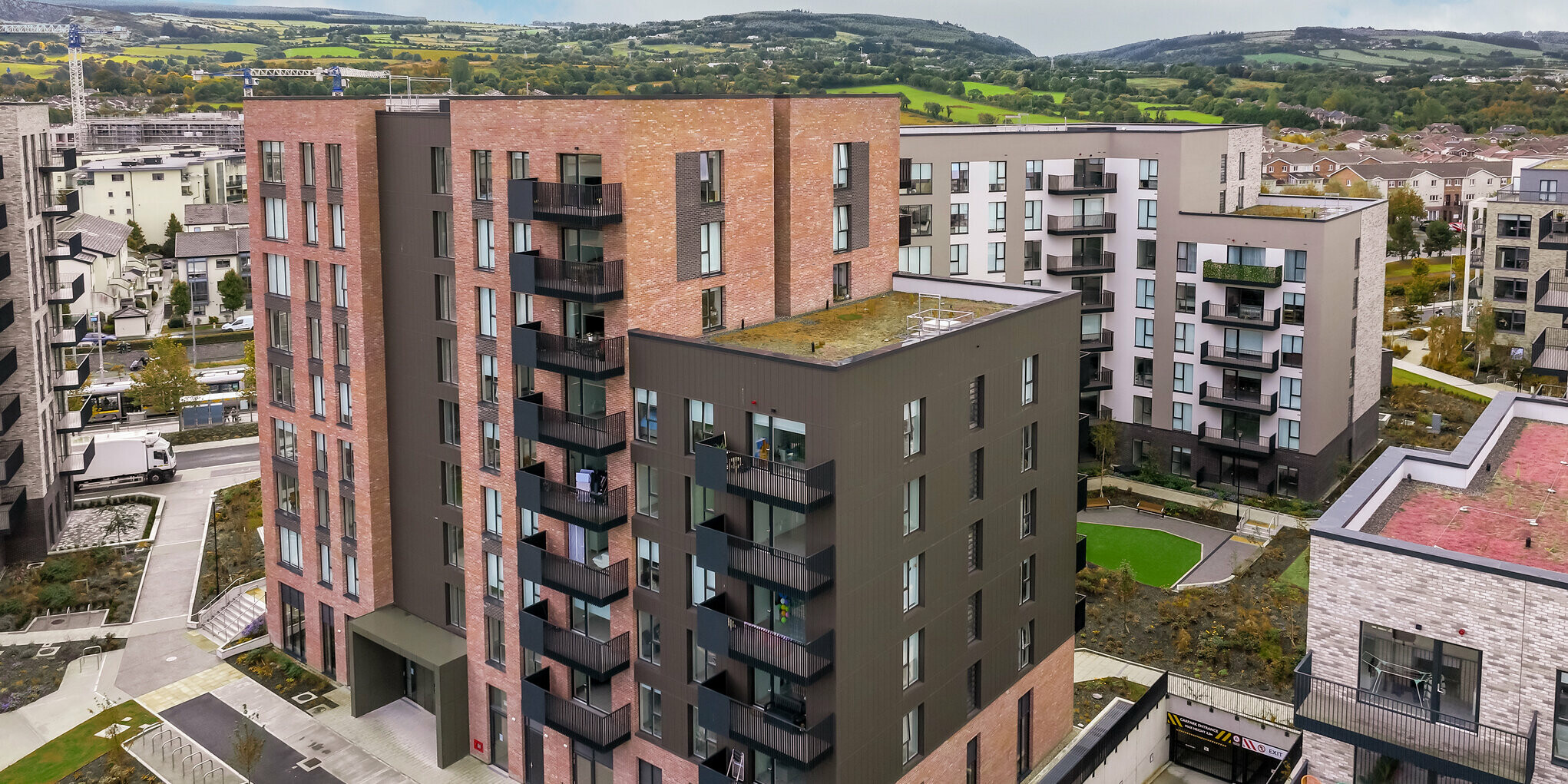 Luftaufnahme der Citywest Apartments in Dublin. Die vertikal verlegten PREFA Sidings in P.10 Braun auf ca. 700 m² ergänzen die traditionelle Backsteinfassade. Moderne Architektur und langlebige Aluminiumfassade verbinden ansprechendes Design mit Witterungsbeständigkeit.